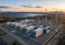 High Efficiency Inverters Transforming Power Systems Renewable energy site at sunset featuring wind turbines, a solar farm, and a highโvoltage substation with transmission lines near a distant city skylineIf needed, keep it concise and avoid starting with 'Image of'